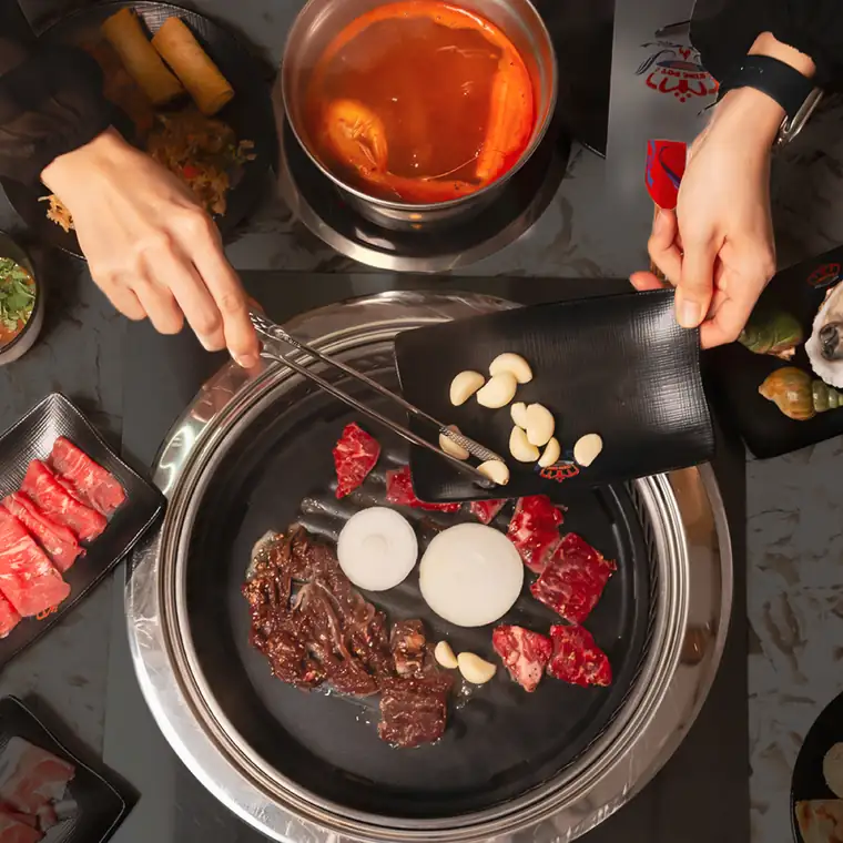 Overhead view of a Korean BBQ grill and hotpot spread